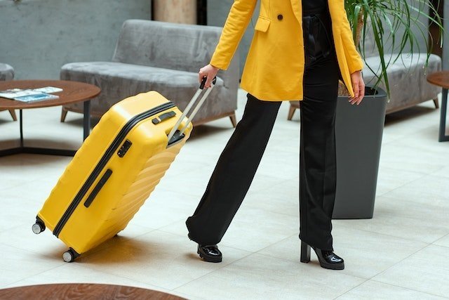 woman in yellow carrying a suitcase