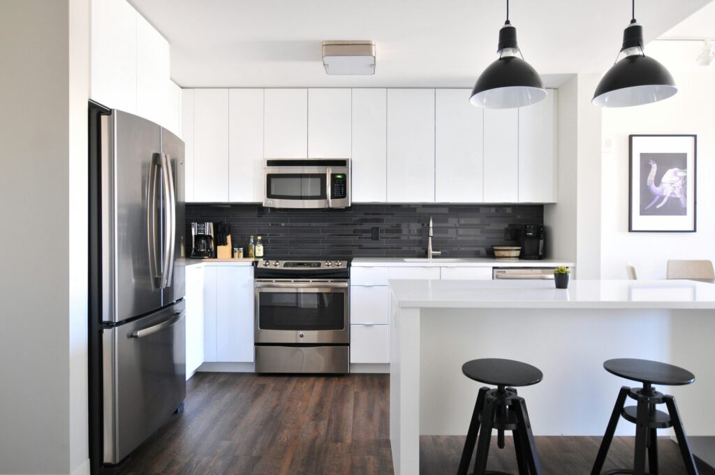 A modern and spotless Airbnb kitchen, featuring sleek white cabinets, stainless steel appliances, and a minimalist design, ensuring a clean and inviting space for guests.